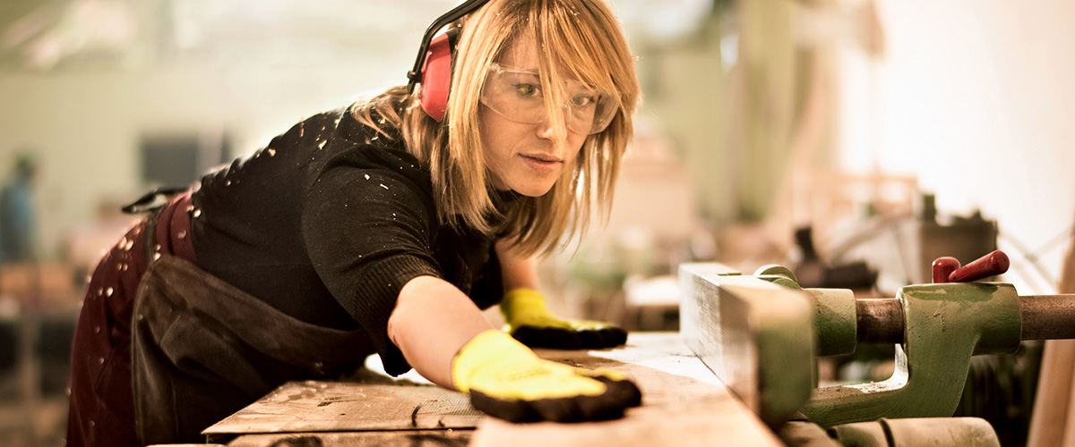 Female carpenter working on a piece of wood.