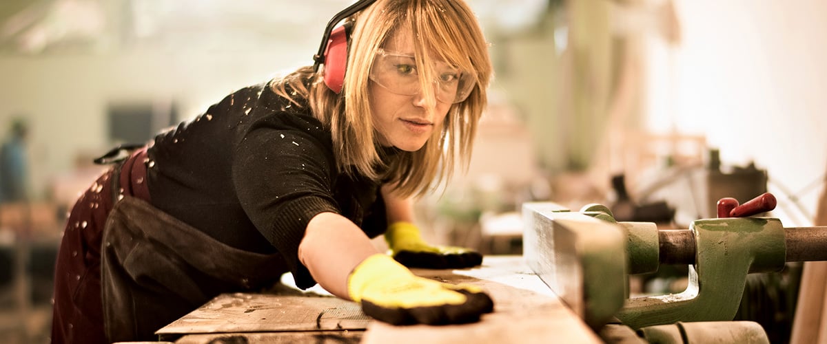 Female carpenter working on a piece of wood.