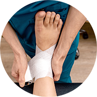 Close shot of a physicians hands bandaging a patients foot