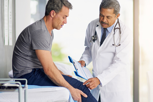 Urgent Care Doctor Examining Man's Knee
