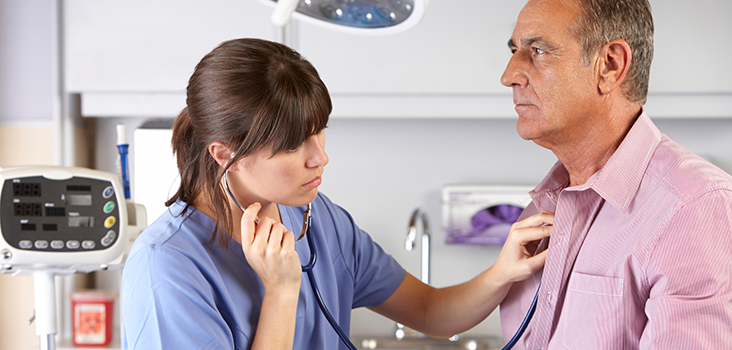 Female physician listening to male patient's heartbeat with stethoscope