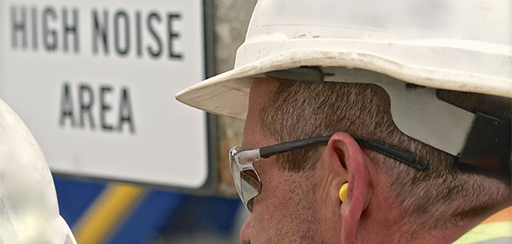Man wearing hard hat and ear plugs in a high noise area
