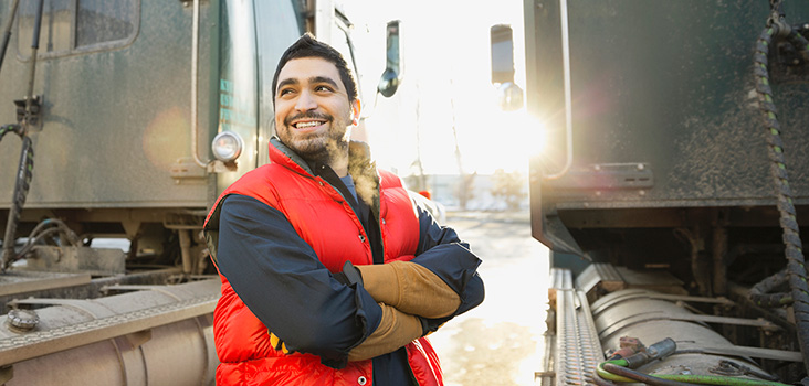 Male truck driver smiling at his semi trucks