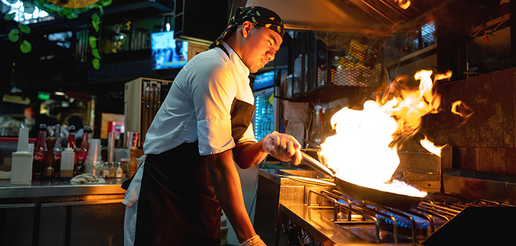 Male chef cooking food with big flames