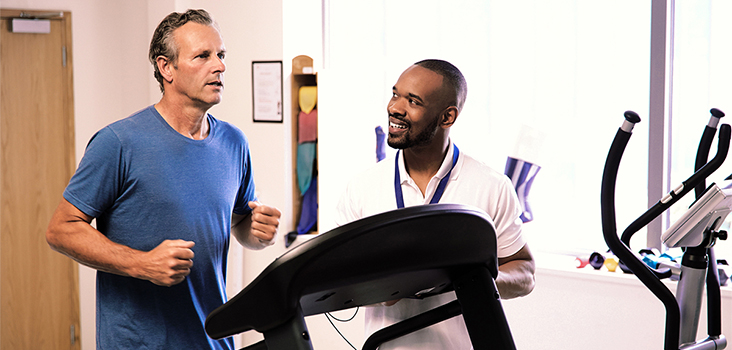 Man running on treadmill while physical therapist evaluates