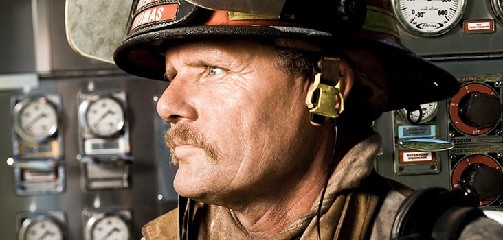 Male firefighter close up wearing firefighter gear.