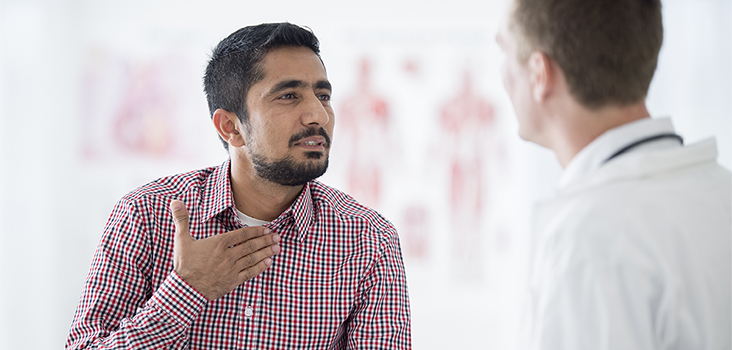 Man touching his throat speaking to male physician 