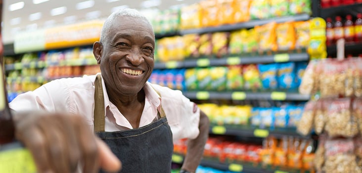 Male grocer chain worker smiling at his job.