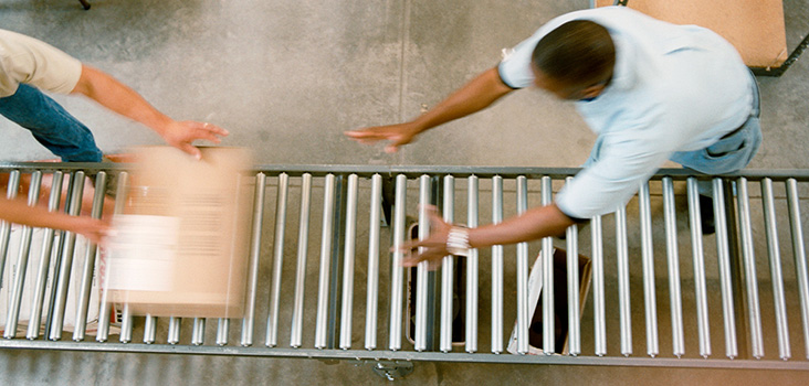 Employees in warehouse passing packages to eachother