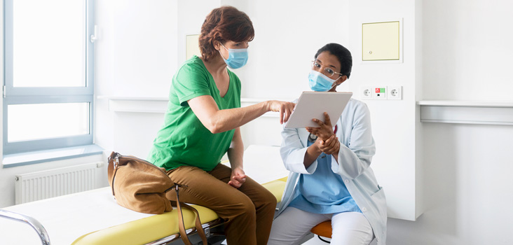 Female physician and patient going over results while wearing masks.