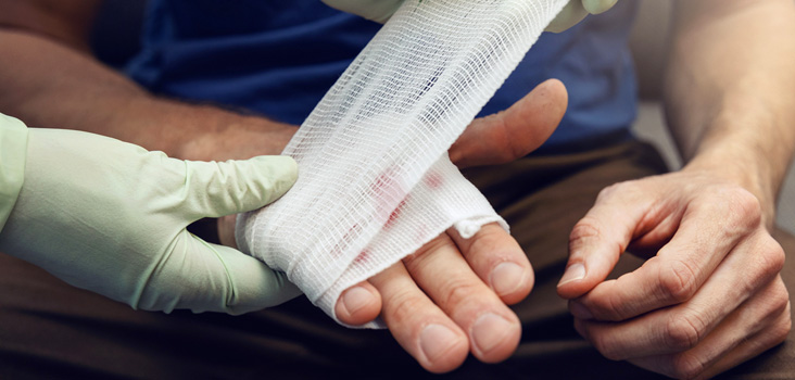 Physician bandaging a patients hand after an injury.