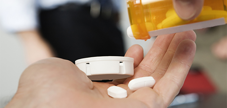 Person taking pills from pill bottle