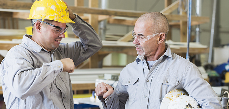Man in yellow hard hat talking to coworker
