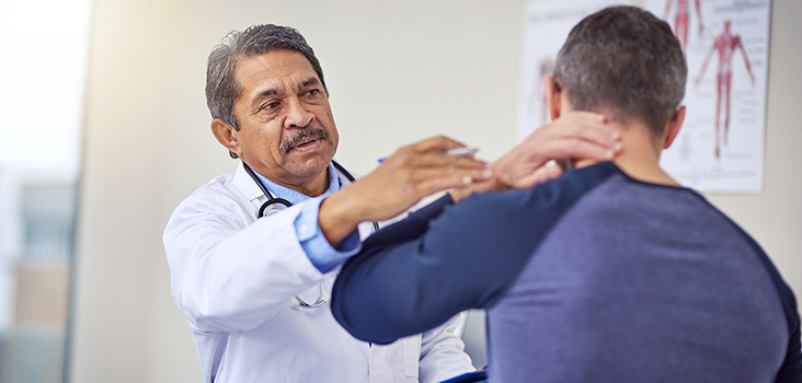 Male physician examines male patient's neck where he feels pain