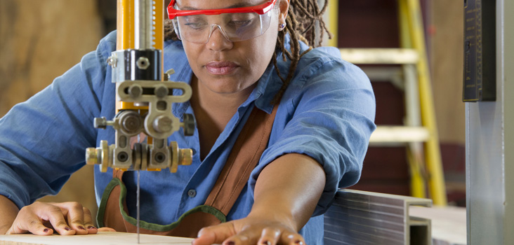 Female carpenter wearing eye gear during drilling to keep her eyes safe.